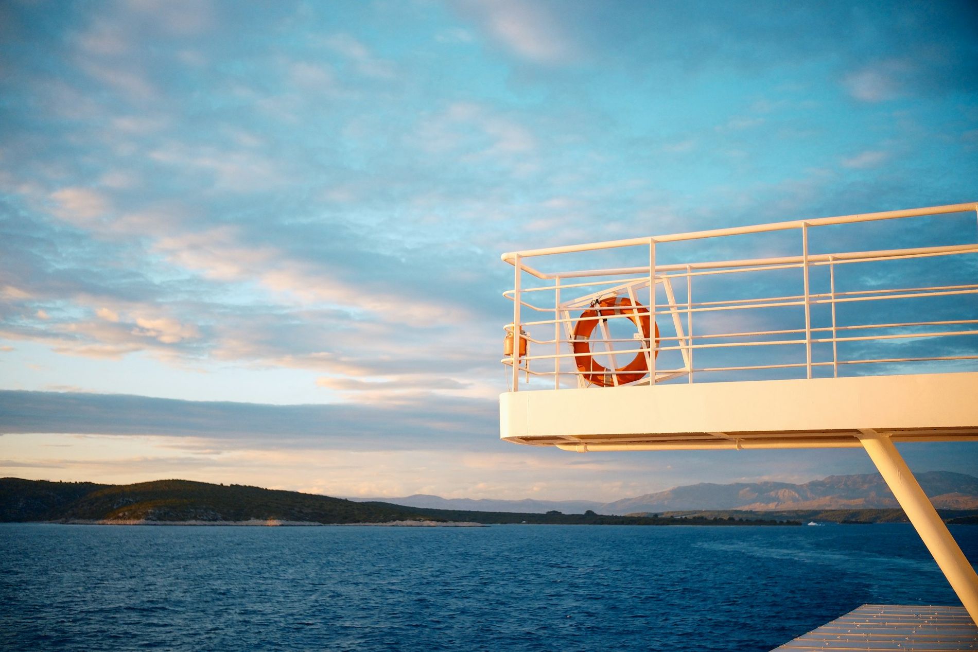 Pont d'un ferry avec une bouée de sauvetage, face à la côte au lever du jour