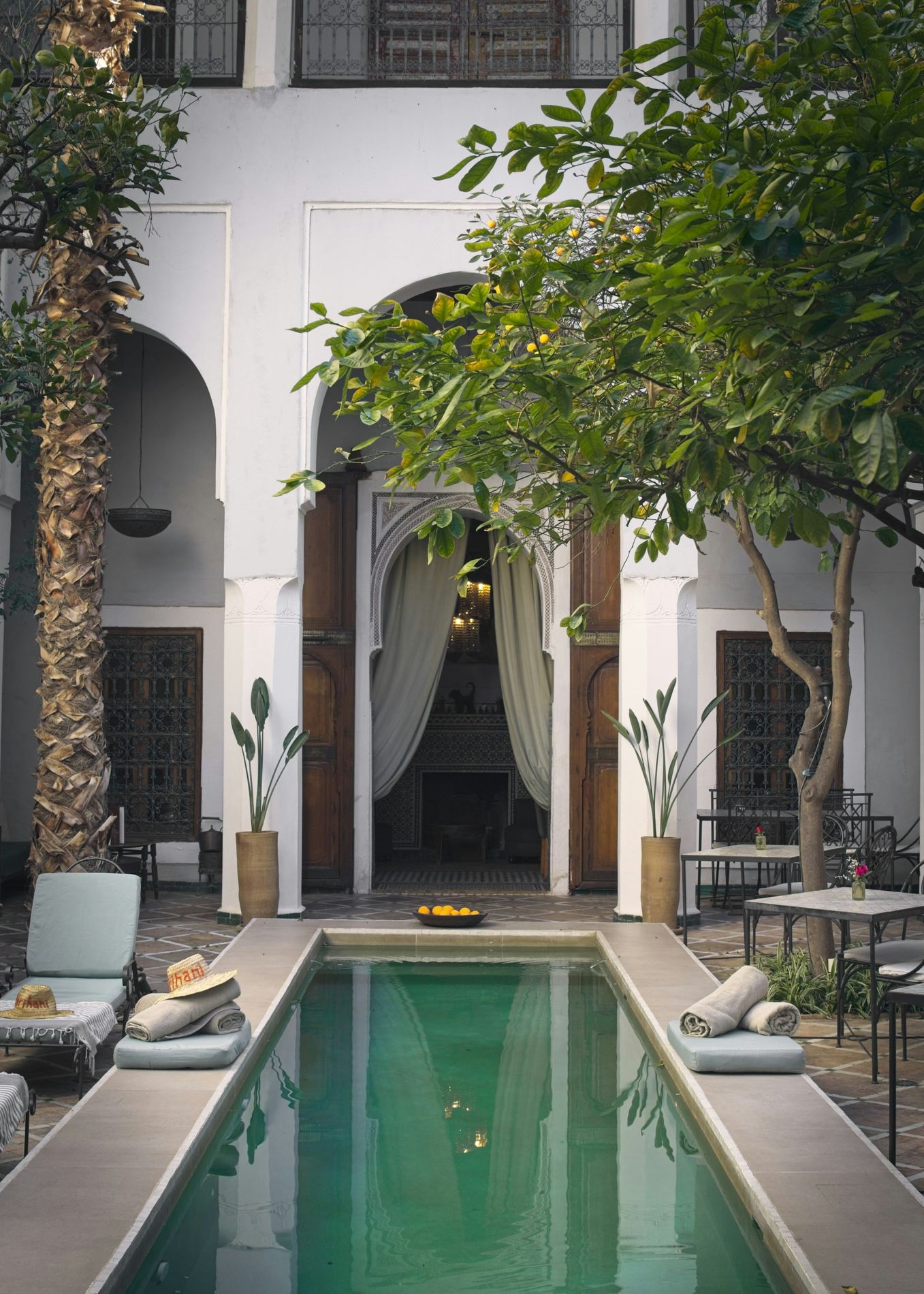 Patio d'un riad avec un bassin et des arcades blanches